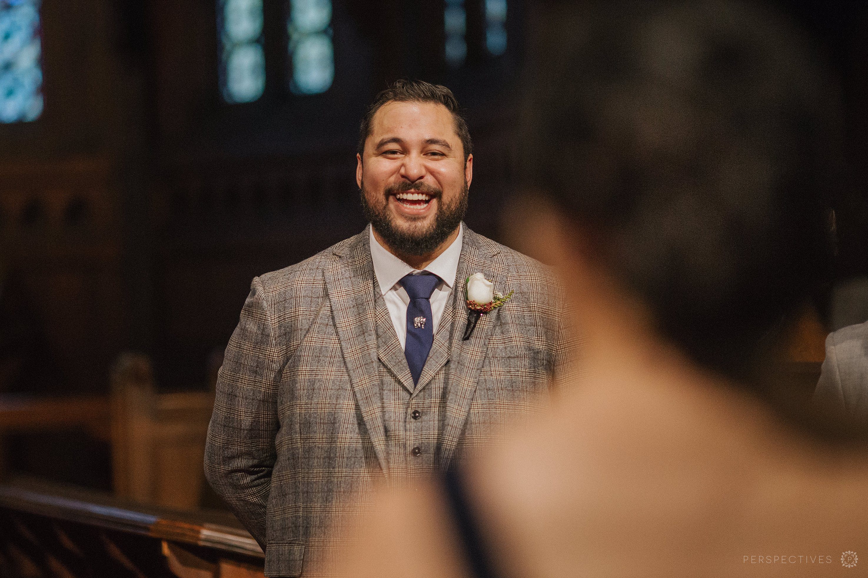 Groom watches bride coming up aisle