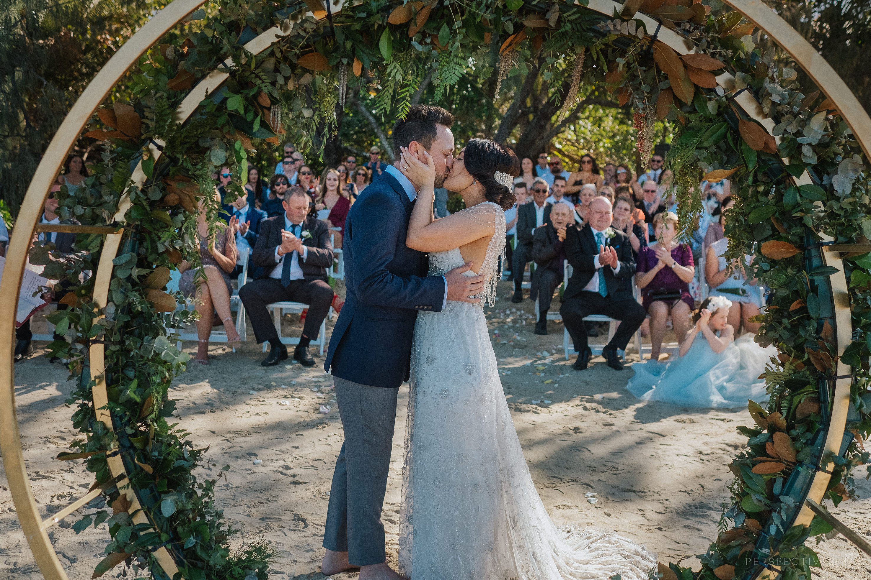 first kiss at wedding with guests clapping