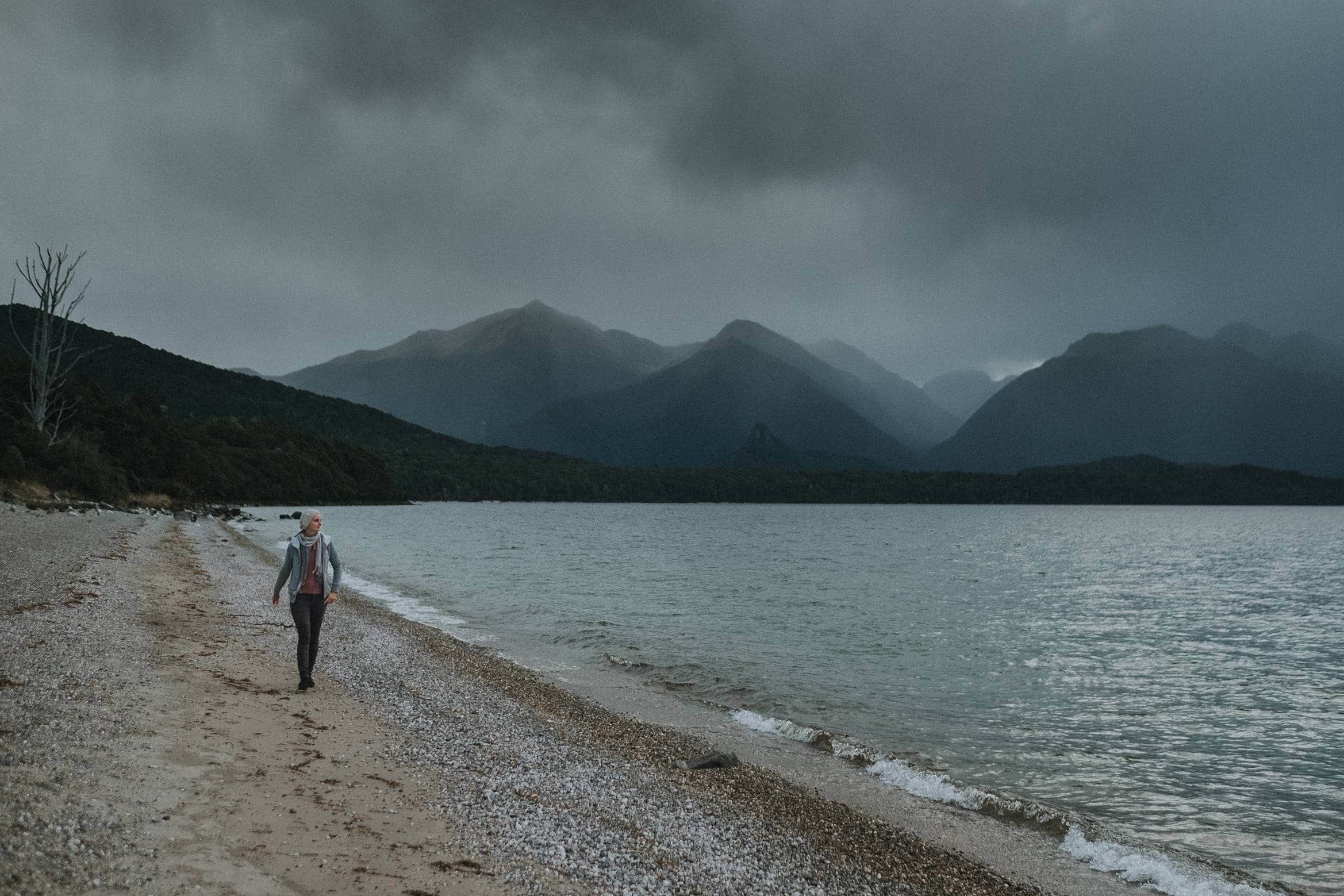 Walking along moody lake Manapouri