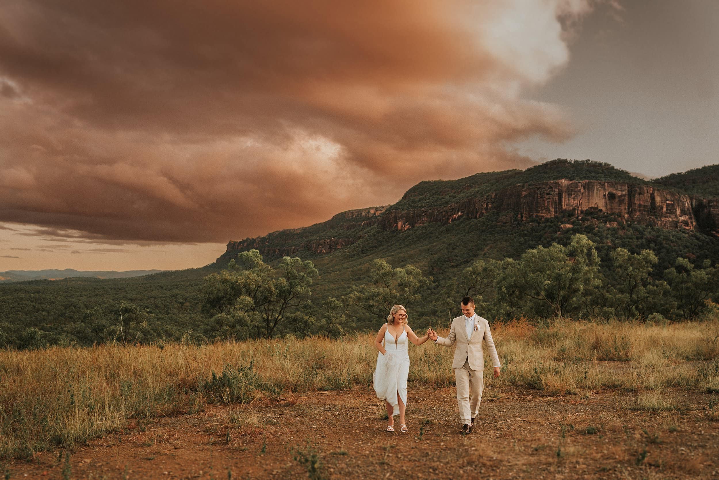 Bride and groom walking under sunset sky at Mount Mulligan lodge wedding