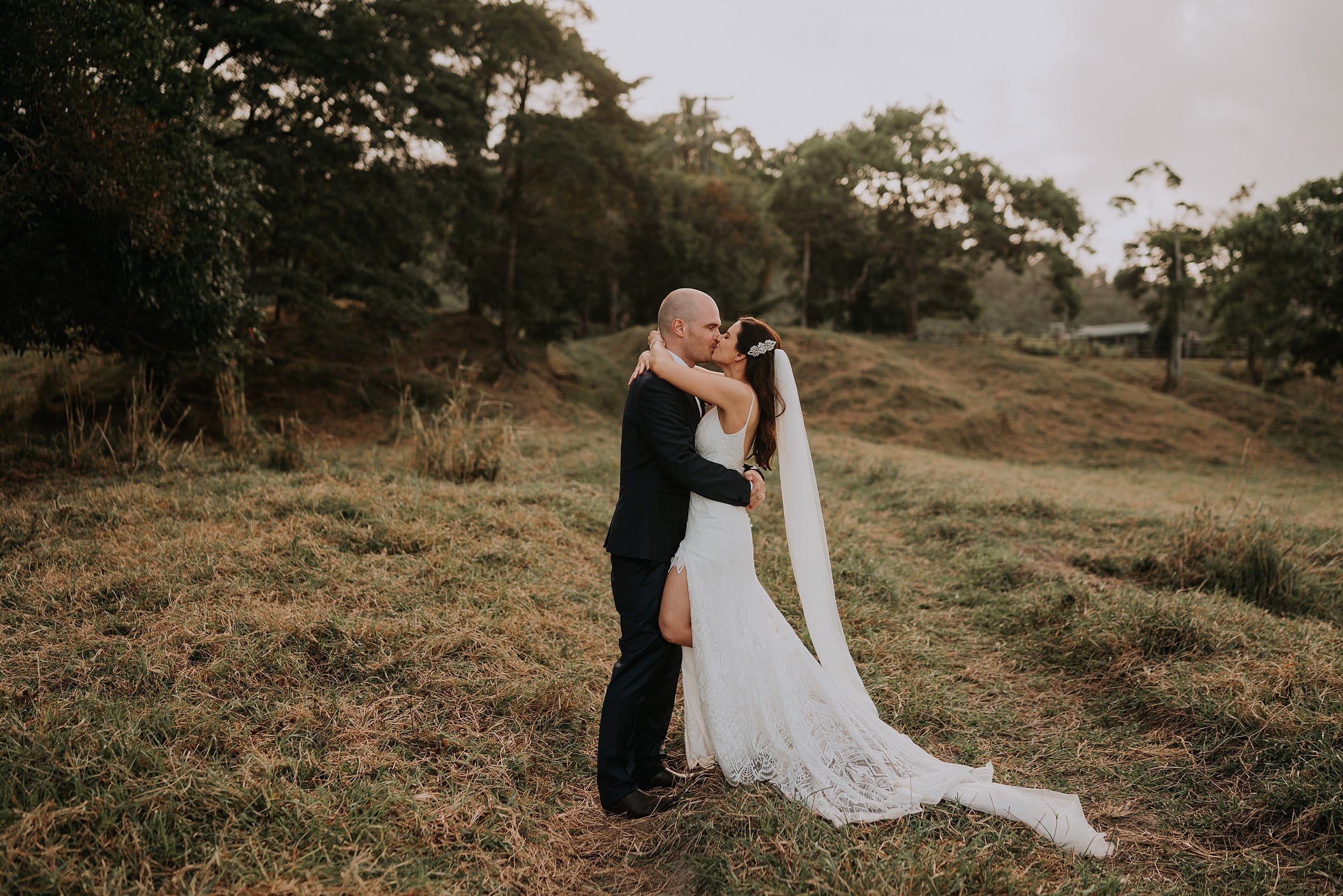 Couple kissing in field on wedding day